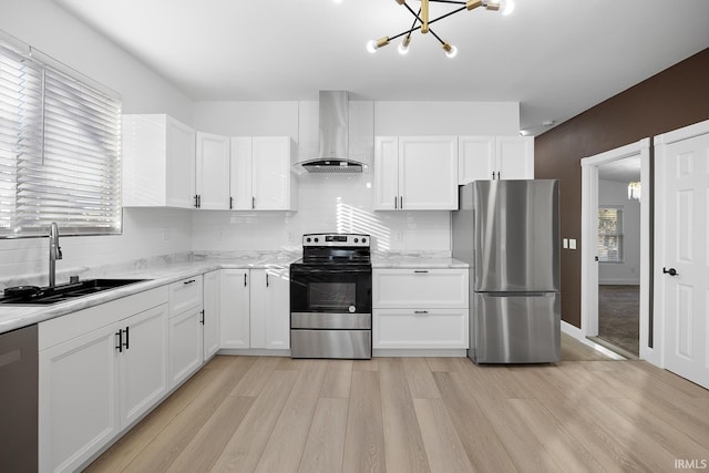 kitchen with appliances with stainless steel finishes, wall chimney exhaust hood, sink, and white cabinetry