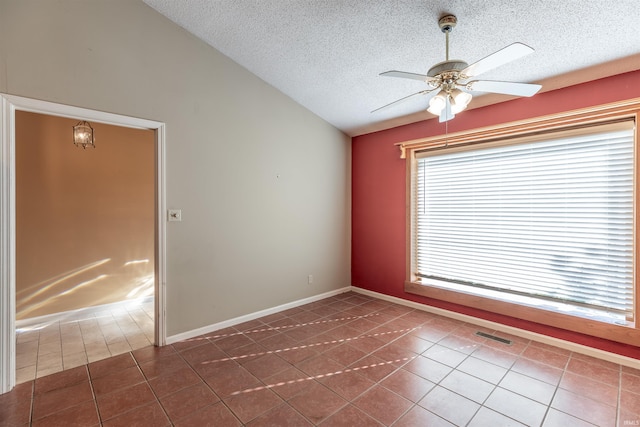 tiled empty room with lofted ceiling, ceiling fan, and a textured ceiling