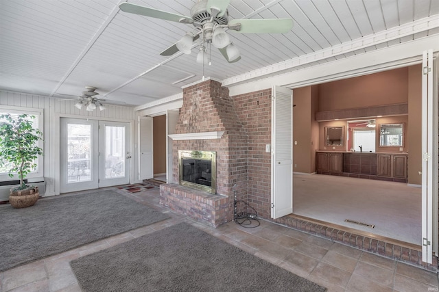 unfurnished living room featuring ceiling fan, plenty of natural light, tile patterned floors, and a fireplace