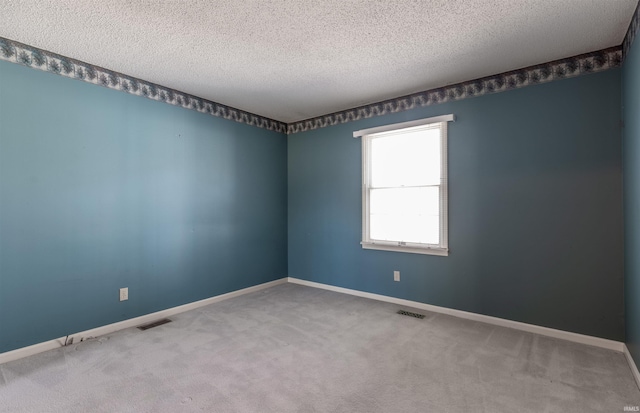 carpeted empty room with a textured ceiling