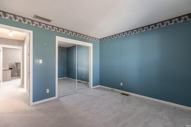 unfurnished bedroom with carpet floors, a closet, and a textured ceiling