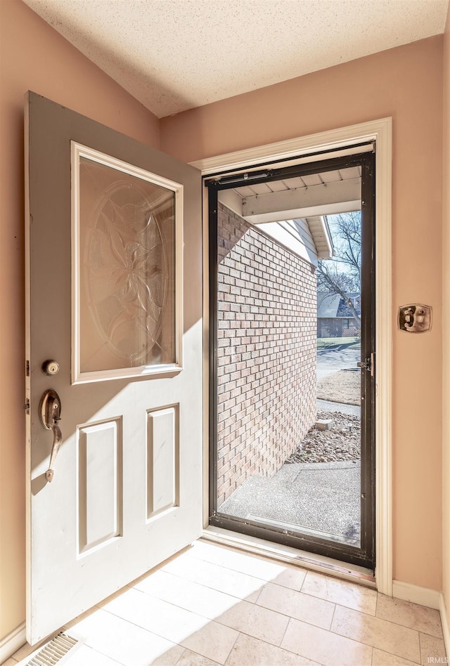 doorway to outside featuring a textured ceiling