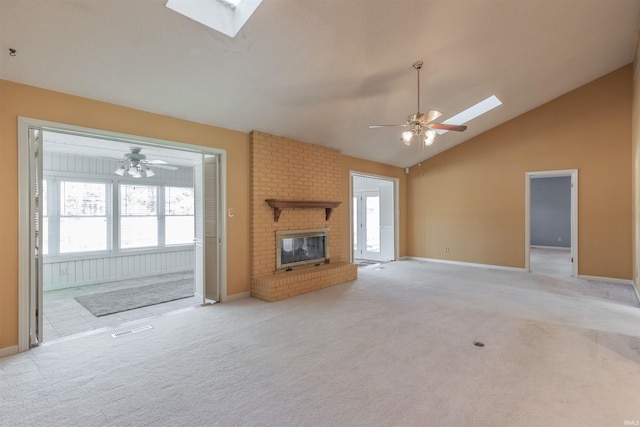 unfurnished living room with light carpet, a brick fireplace, vaulted ceiling with skylight, and ceiling fan