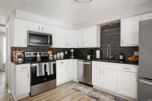 kitchen with white cabinetry, appliances with stainless steel finishes, tasteful backsplash, light hardwood / wood-style flooring, and sink