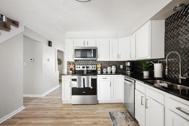 kitchen with backsplash, light hardwood / wood-style floors, sink, appliances with stainless steel finishes, and white cabinets