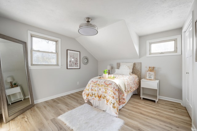 bedroom with lofted ceiling and light hardwood / wood-style floors