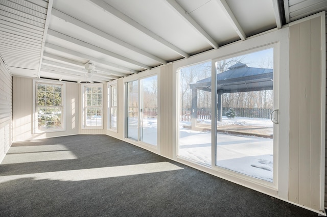 unfurnished sunroom featuring a healthy amount of sunlight and beamed ceiling