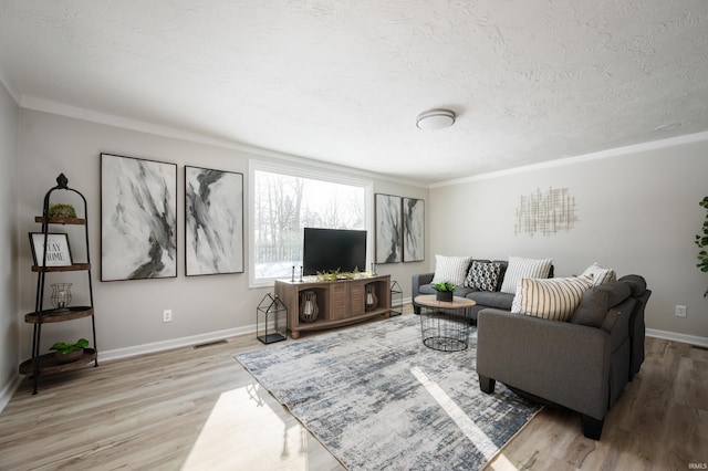 living room featuring a textured ceiling, ornamental molding, and light hardwood / wood-style flooring