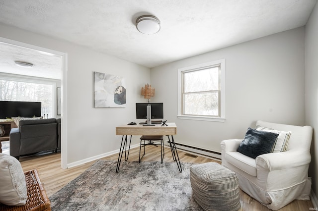 home office with a healthy amount of sunlight, a textured ceiling, light hardwood / wood-style floors, and a baseboard radiator