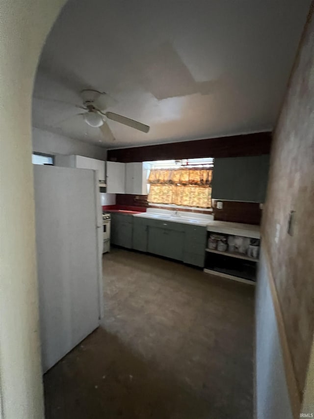 kitchen featuring ceiling fan, white cabinets, white fridge, and concrete flooring