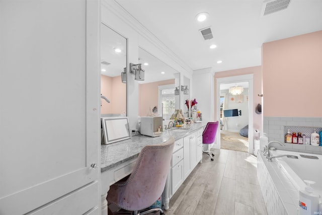 bathroom featuring tiled tub and vanity