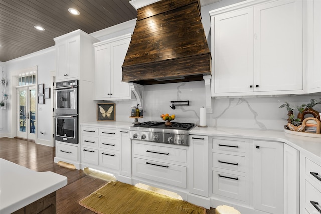 kitchen featuring white cabinets, dark wood-type flooring, stainless steel appliances, tasteful backsplash, and premium range hood