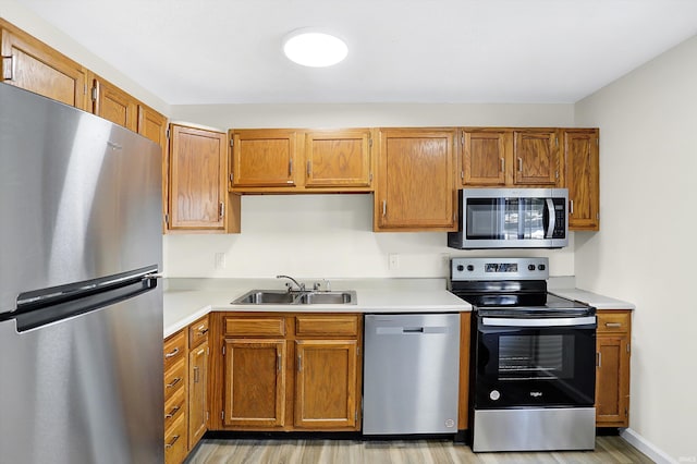 kitchen with stainless steel appliances, light hardwood / wood-style flooring, and sink