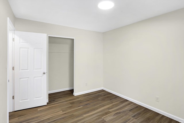 unfurnished bedroom with a closet and dark hardwood / wood-style floors