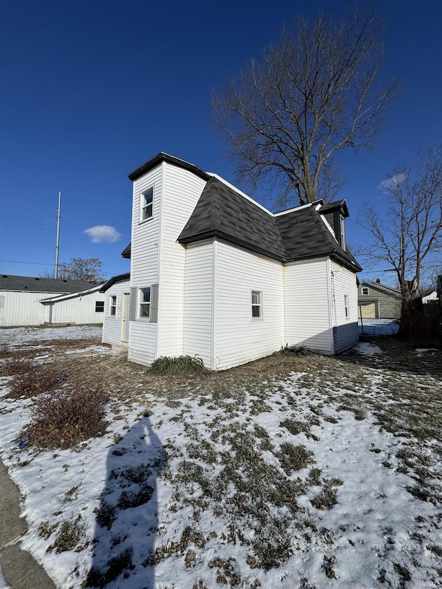 view of snowy exterior featuring roof with shingles