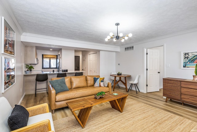 living room with crown molding, light hardwood / wood-style flooring, and a notable chandelier