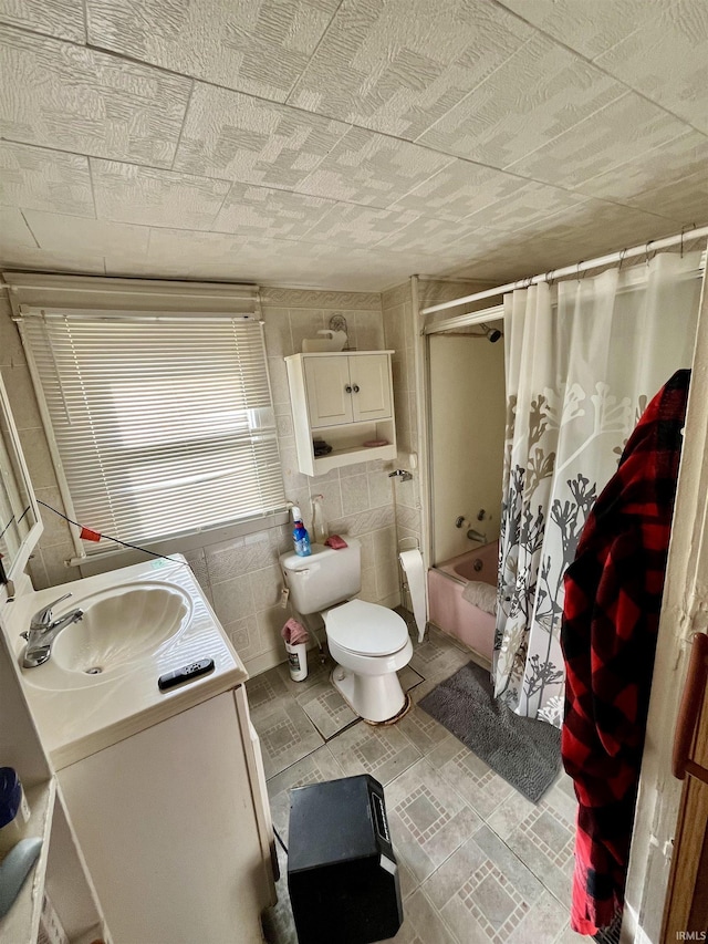 full bathroom with tile walls, toilet, vanity, and shower / bath combo