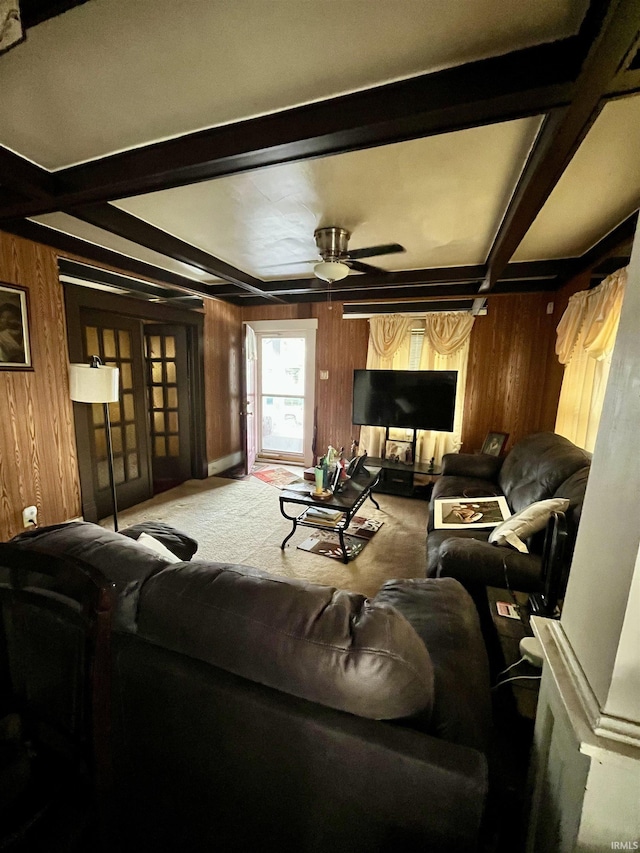 living room featuring carpet floors, beam ceiling, wood walls, and ceiling fan