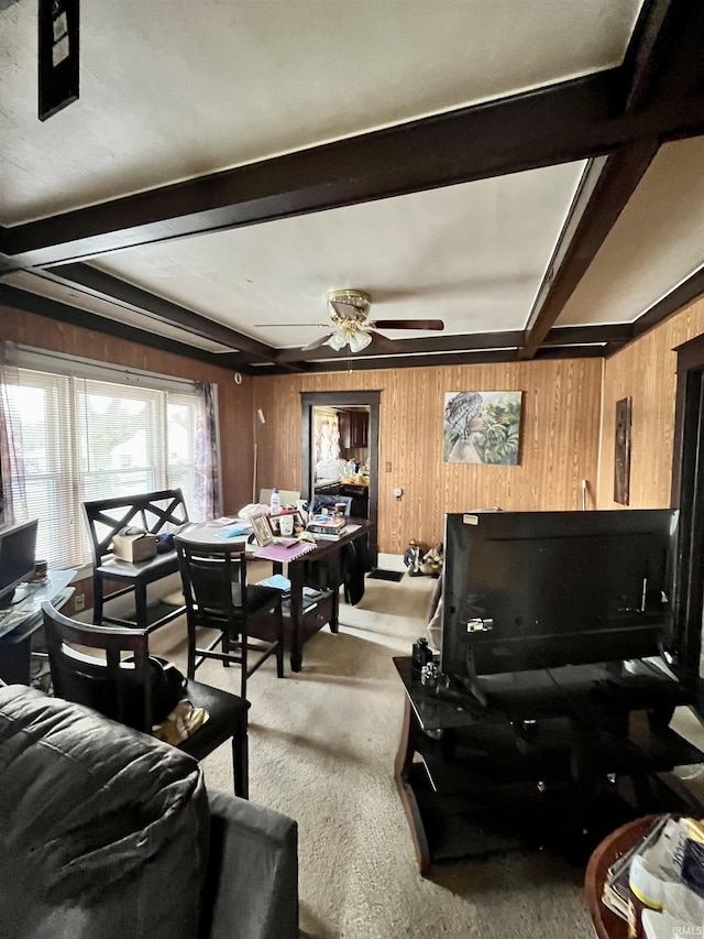 carpeted living room with beam ceiling, wood walls, and ceiling fan