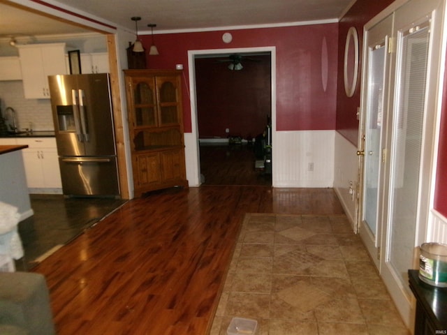 interior space featuring crown molding, pendant lighting, stainless steel fridge, white cabinetry, and decorative backsplash