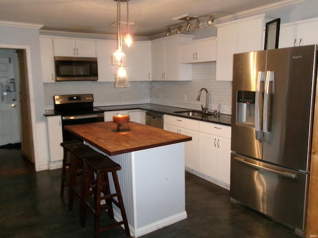 kitchen featuring appliances with stainless steel finishes, white cabinets, a kitchen island, sink, and hanging light fixtures