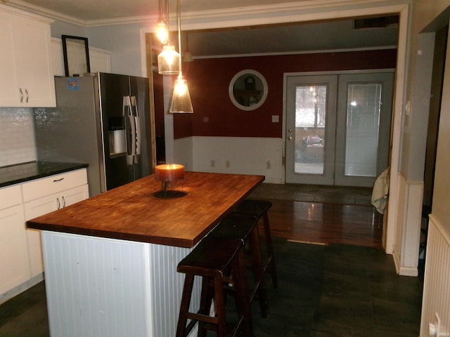 kitchen featuring a kitchen breakfast bar, pendant lighting, stainless steel fridge, white cabinets, and a center island