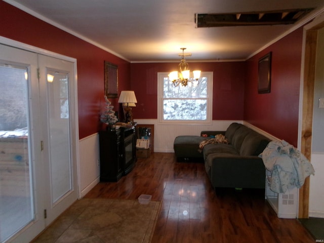 living room featuring dark wood-type flooring, ornamental molding, and a notable chandelier