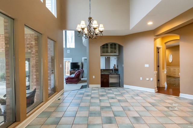 empty room with an inviting chandelier, light tile patterned flooring, and a towering ceiling