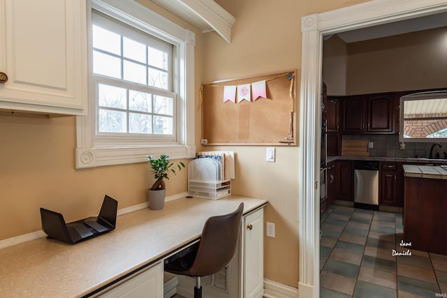 interior space featuring dishwasher, dark tile patterned flooring, built in desk, sink, and dark brown cabinets