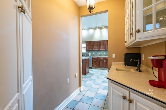 kitchen with white cabinets, dishwasher, sink, backsplash, and light tile patterned floors