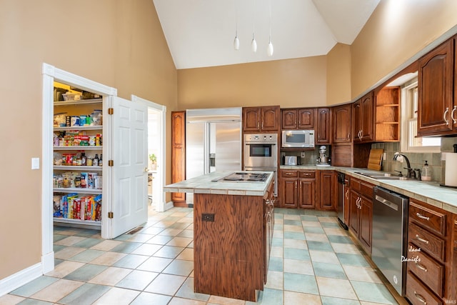 kitchen with tile counters, a center island, high vaulted ceiling, built in appliances, and sink