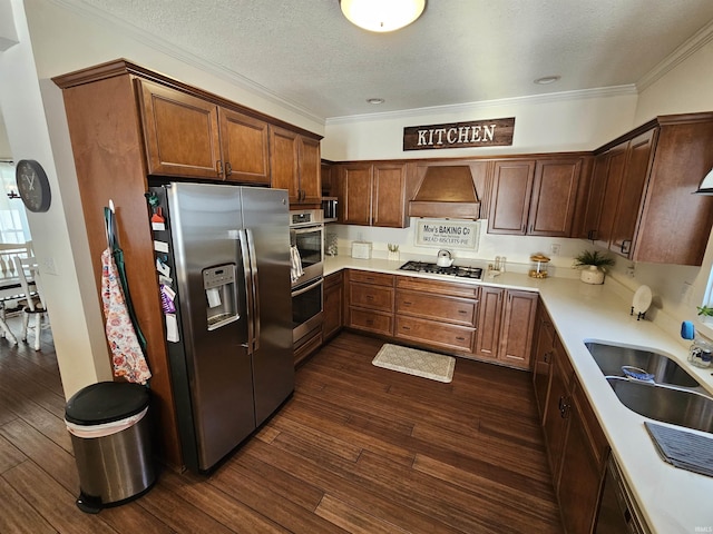 kitchen with a textured ceiling, appliances with stainless steel finishes, dark hardwood / wood-style flooring, and wall chimney range hood