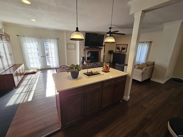 kitchen with decorative light fixtures, a fireplace, a center island, a textured ceiling, and french doors