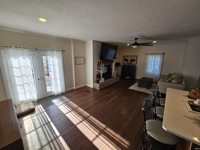 living room with a textured ceiling, dark wood-type flooring, a fireplace, and french doors