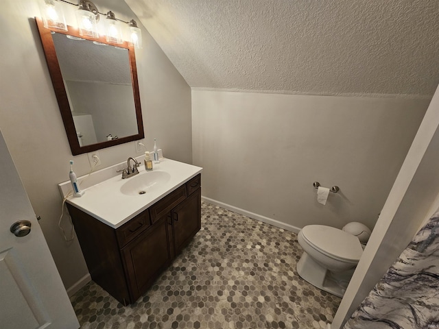 bathroom featuring a textured ceiling, toilet, vanity, and lofted ceiling