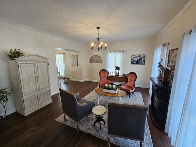 living area with dark wood-type flooring, a textured ceiling, ornamental molding, and an inviting chandelier