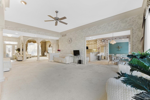 carpeted living room with ceiling fan, crown molding, and decorative columns