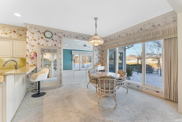 carpeted dining room featuring crown molding and sink