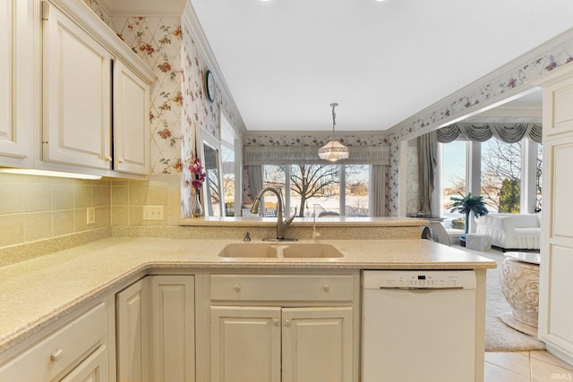 kitchen with pendant lighting, sink, light tile patterned flooring, white dishwasher, and cream cabinetry