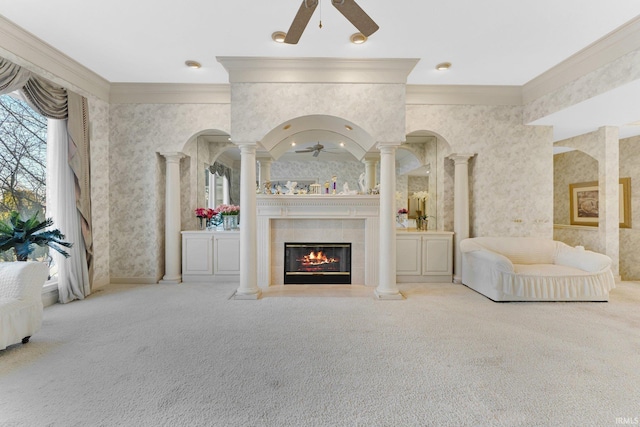 unfurnished living room featuring ceiling fan, light colored carpet, crown molding, and ornate columns