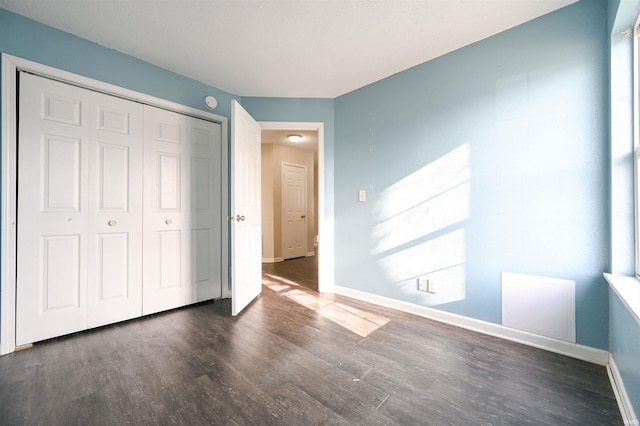 unfurnished bedroom with dark hardwood / wood-style floors and a closet