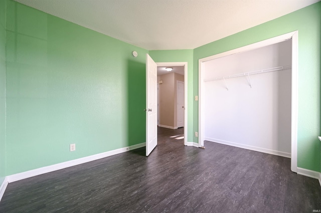 unfurnished bedroom with a closet and dark wood-type flooring