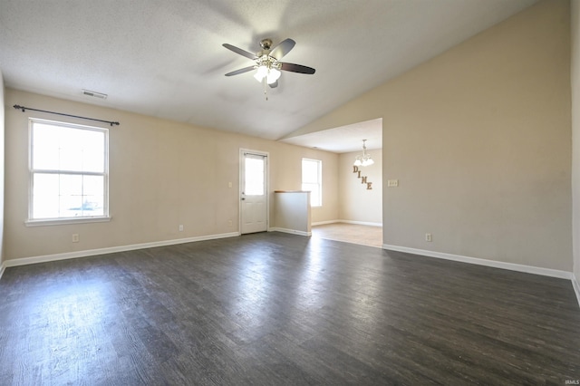 spare room with vaulted ceiling, dark wood-type flooring, ceiling fan with notable chandelier, and plenty of natural light