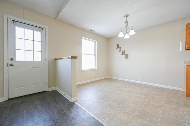 interior space with a textured ceiling, a wealth of natural light, light hardwood / wood-style floors, and a chandelier