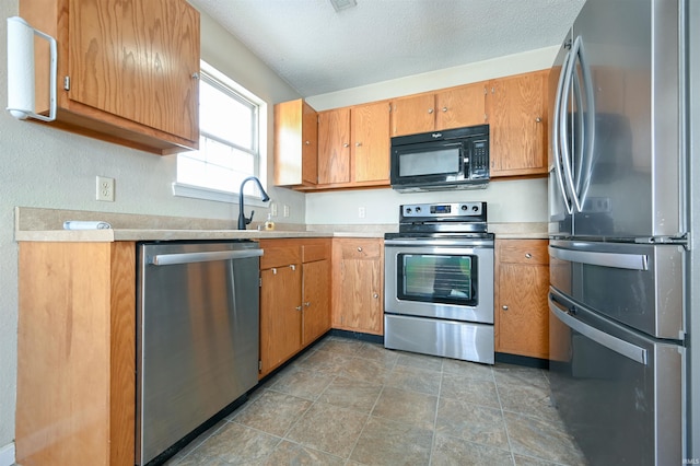 kitchen featuring appliances with stainless steel finishes, sink, and a textured ceiling