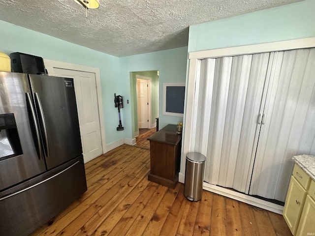 kitchen featuring stainless steel refrigerator with ice dispenser, a textured ceiling, and hardwood / wood-style flooring