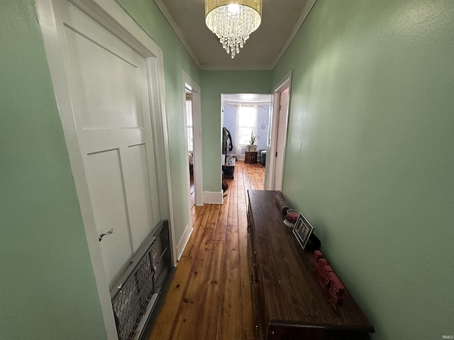 hall with crown molding, a chandelier, and hardwood / wood-style floors