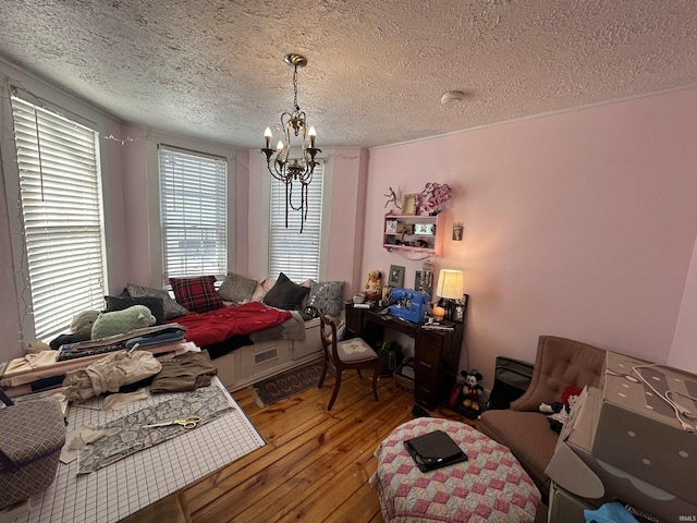 bedroom featuring a textured ceiling, a chandelier, wood-type flooring, and multiple windows