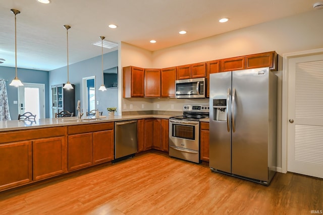 kitchen featuring light hardwood / wood-style floors, sink, hanging light fixtures, and appliances with stainless steel finishes