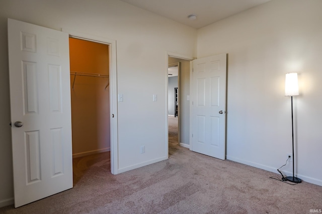 unfurnished bedroom with light carpet, a closet, and a walk in closet